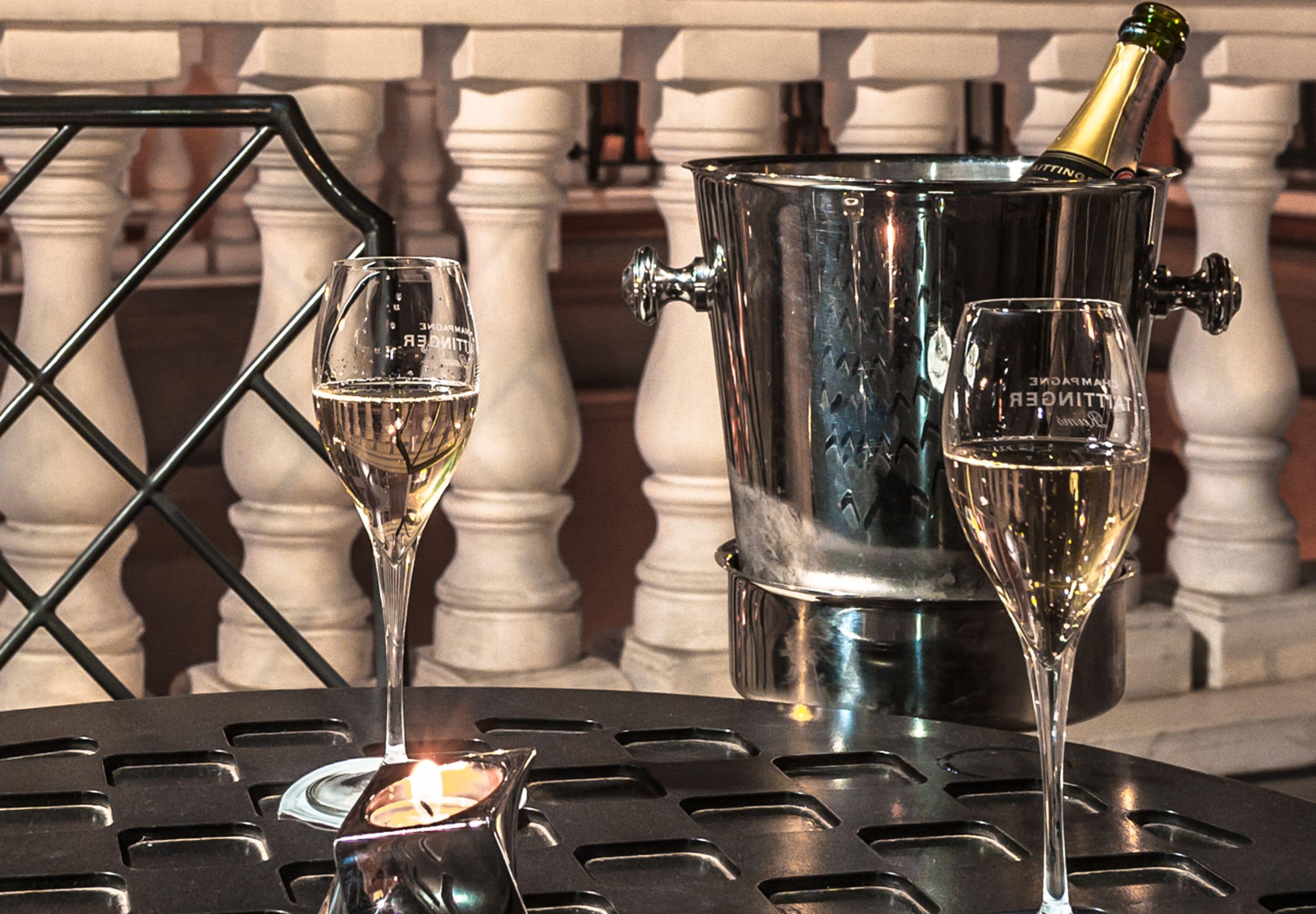 Een tafel met twee champagneglazen en een fles in een metalen houder.