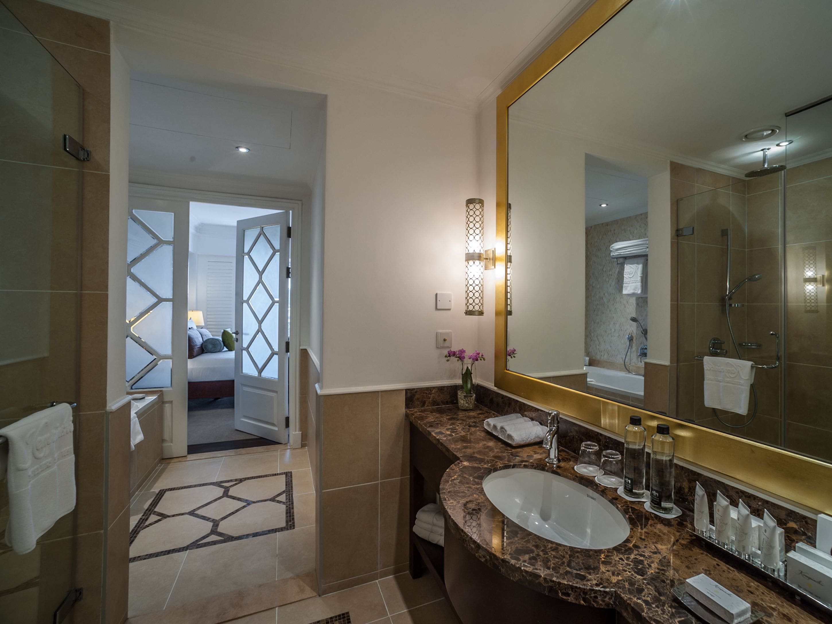 Un baño moderno con un espejo grande, un lavamanos y una ducha.
