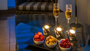 A glass table with candles, fruit bowls, and two glasses of wine.