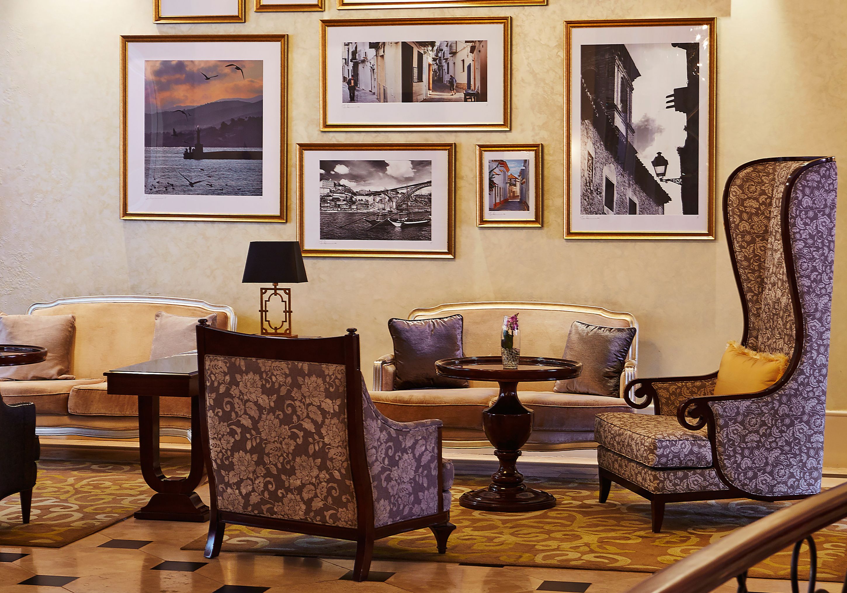 A lobby with a sofa, chairs, a table, and framed pictures on the wall.