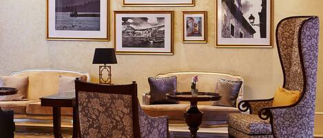 Un hall d’entrée avec un canapé, des fauteuils, une table et des tableaux encadrés accrochés au mur.