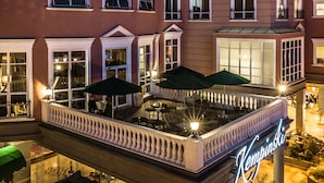 A hotel with a rooftop terrace featuring outdoor seating and umbrellas.