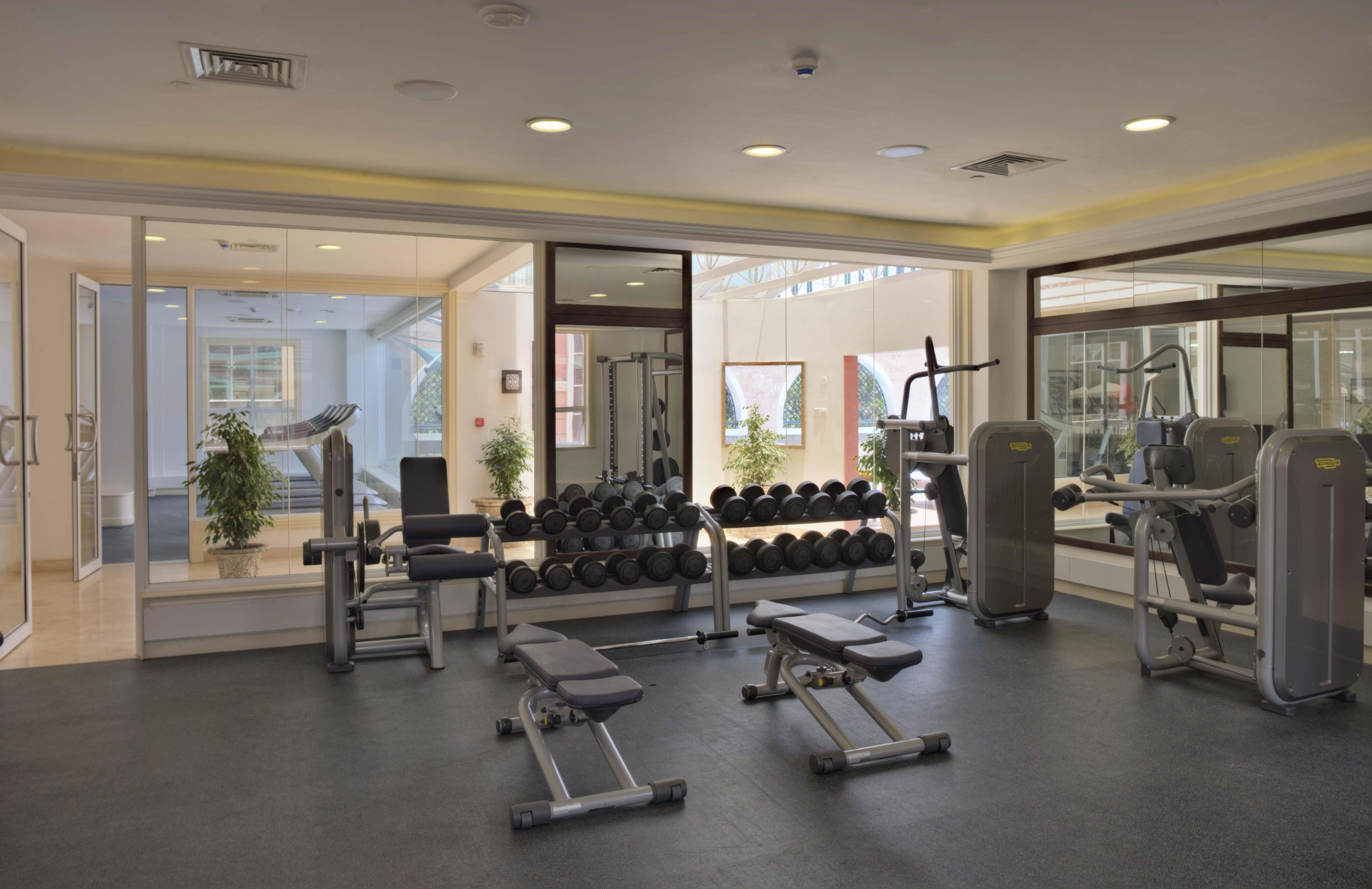 A gym with various exercise equipment, including dumbbells and weight machines, and a bench.