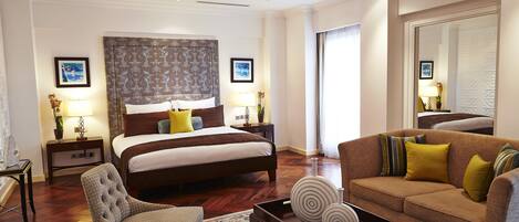 Una habitación de hotel con una cama grande, un sofá, una silla, una mesita de centro y una araña.