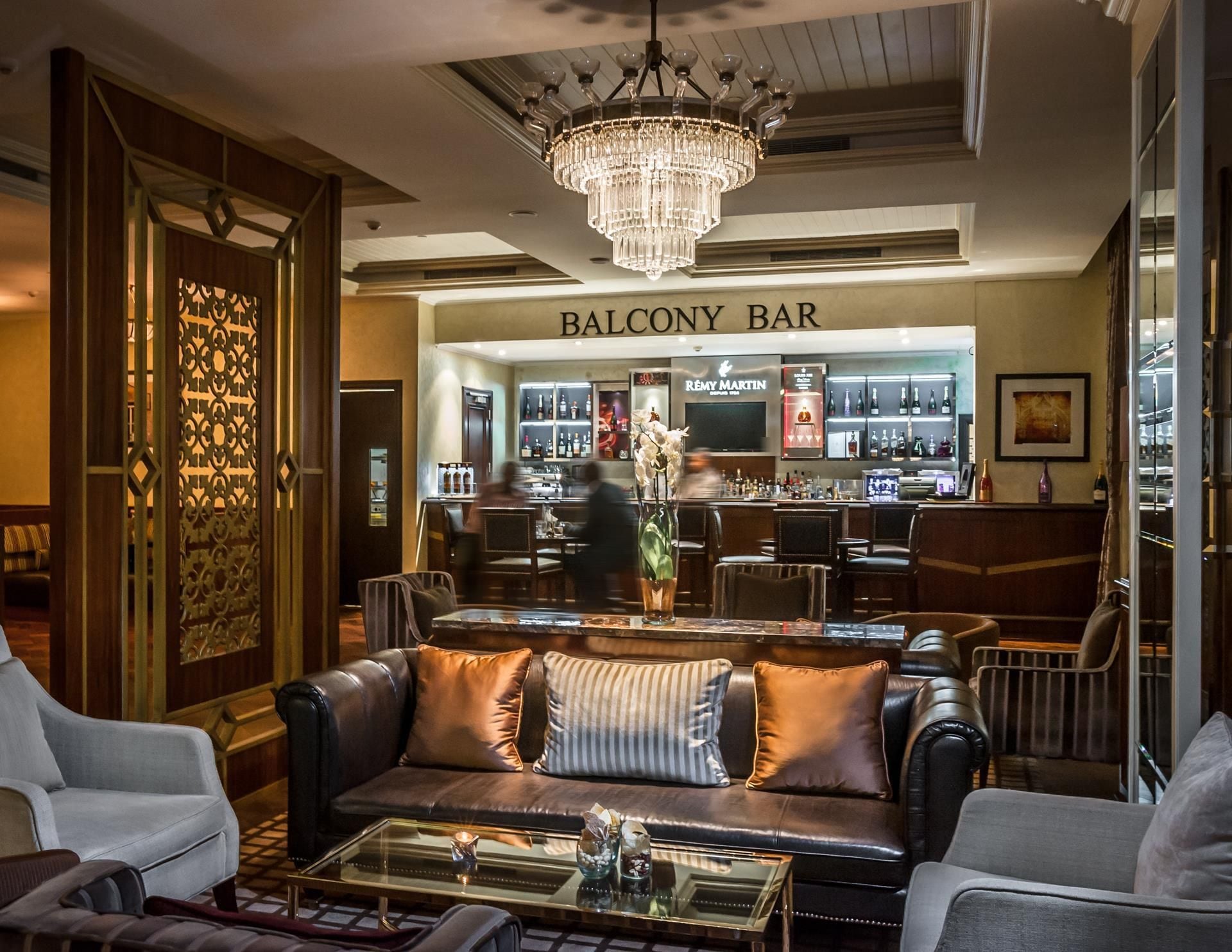 Zona de bar con candelabro, asientos de cuero y barra.