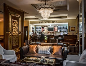 Zona de bar con candelabro, asientos de cuero y barra.