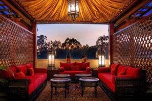 A cozy lounge area with red sofas, small round tables, and decorative lanterns. - Villa Rosa Kempinski (Nairobi)
