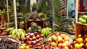 A fruit stand with various fruits and a tropical plant in the background.