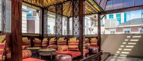 Un interior tradicional con muebles de madera, cojines estampados y suelo de baldosas.