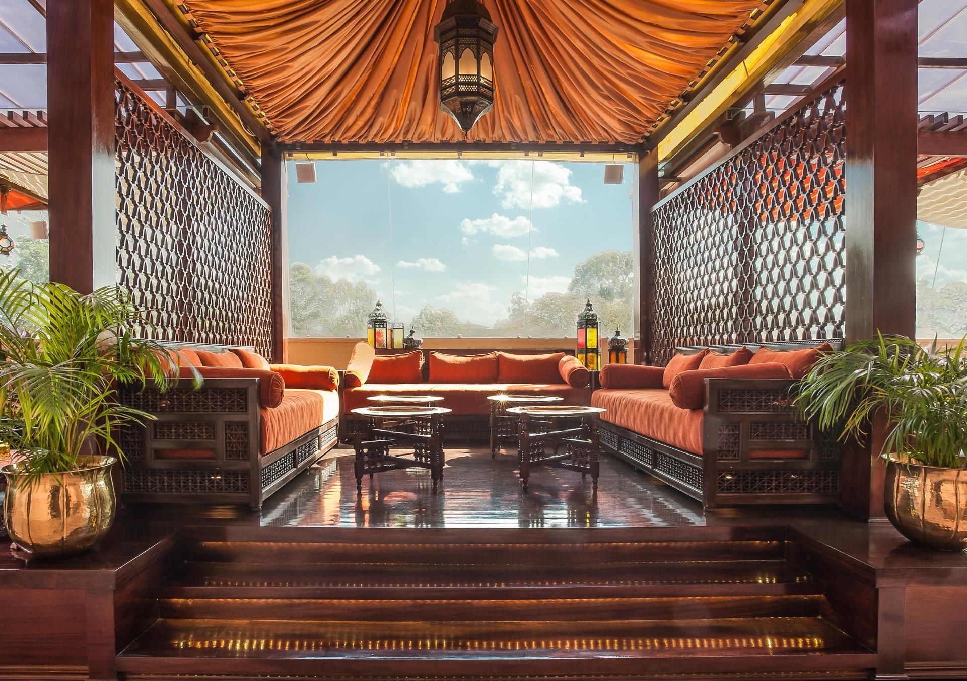 Un espacio de estar amplio con vistas al exterior, que incluye un conjunto de sofás, una mesa de centro y faroles decorativos.