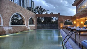 A pool area with a waterfall feature, lounge chairs, and a bar area with a tiled backsplash.