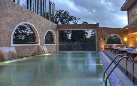 A pool area with a waterfall feature, lounge chairs, and a bar area with a tiled backsplash.