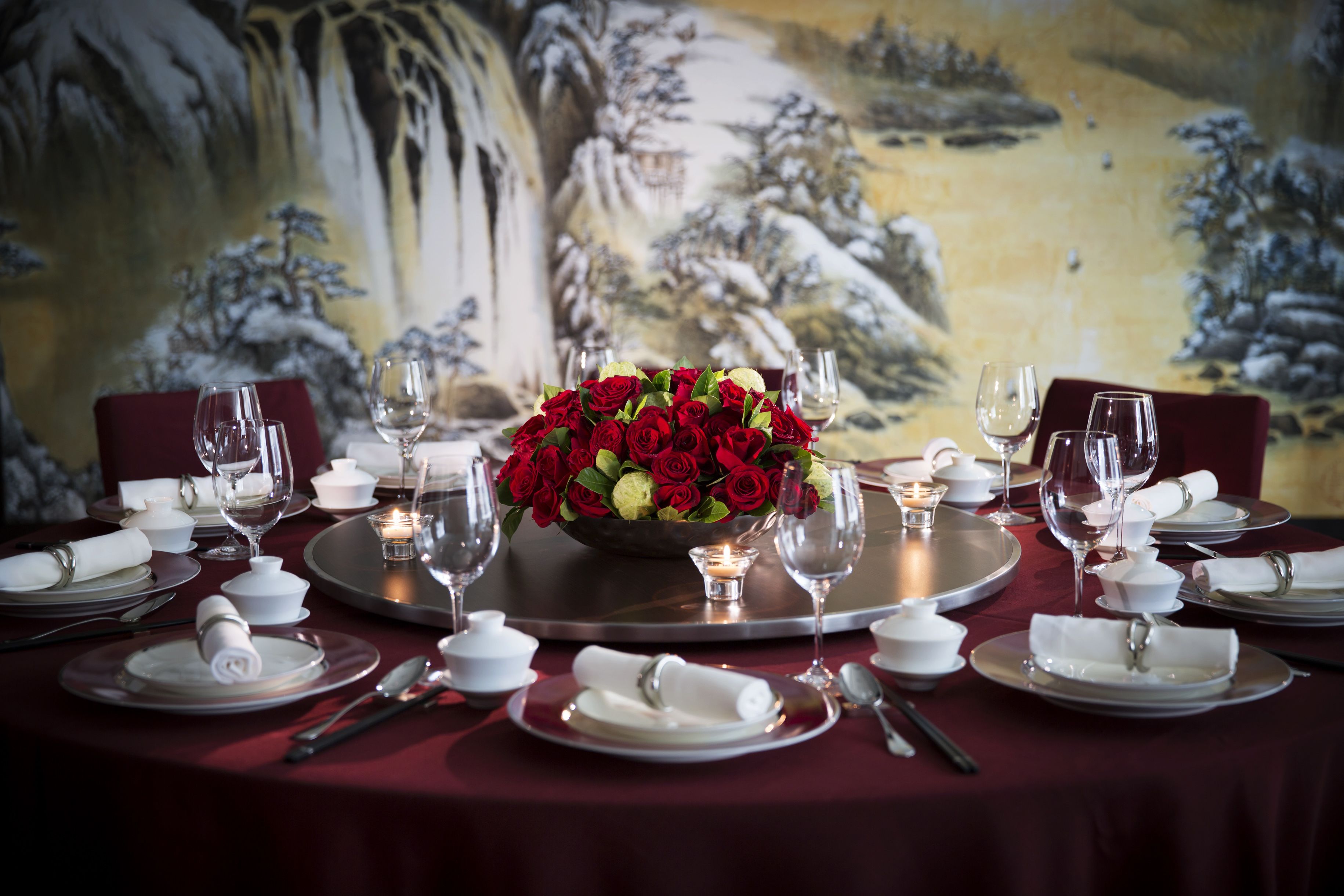 A table set for a formal dinner with a floral centerpiece, white napkins, and wine glasses.