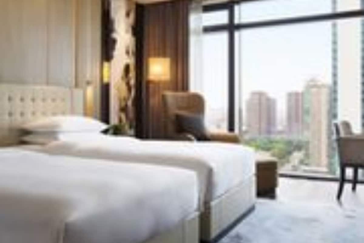 A hotel room with two beds, a large window with a city view, and a modern design.
