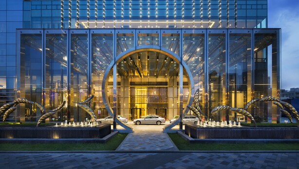 A modern building with a glass facade, a central arch entrance, and a car parked in front. - Grand Hyatt Shenyang (Shenyang)