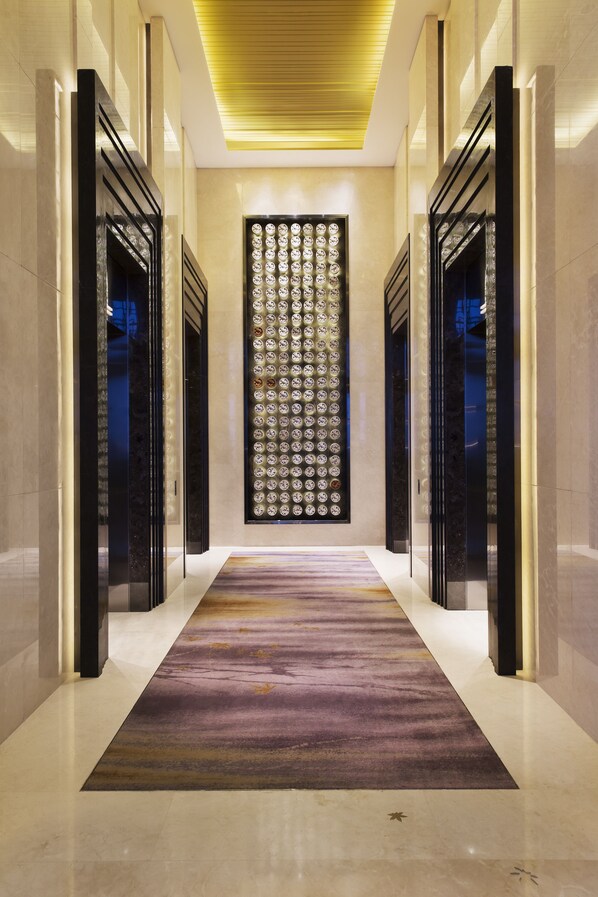 Un couloir moderne avec un mur à motifs, des portes à cadre noir et un tapis coloré.