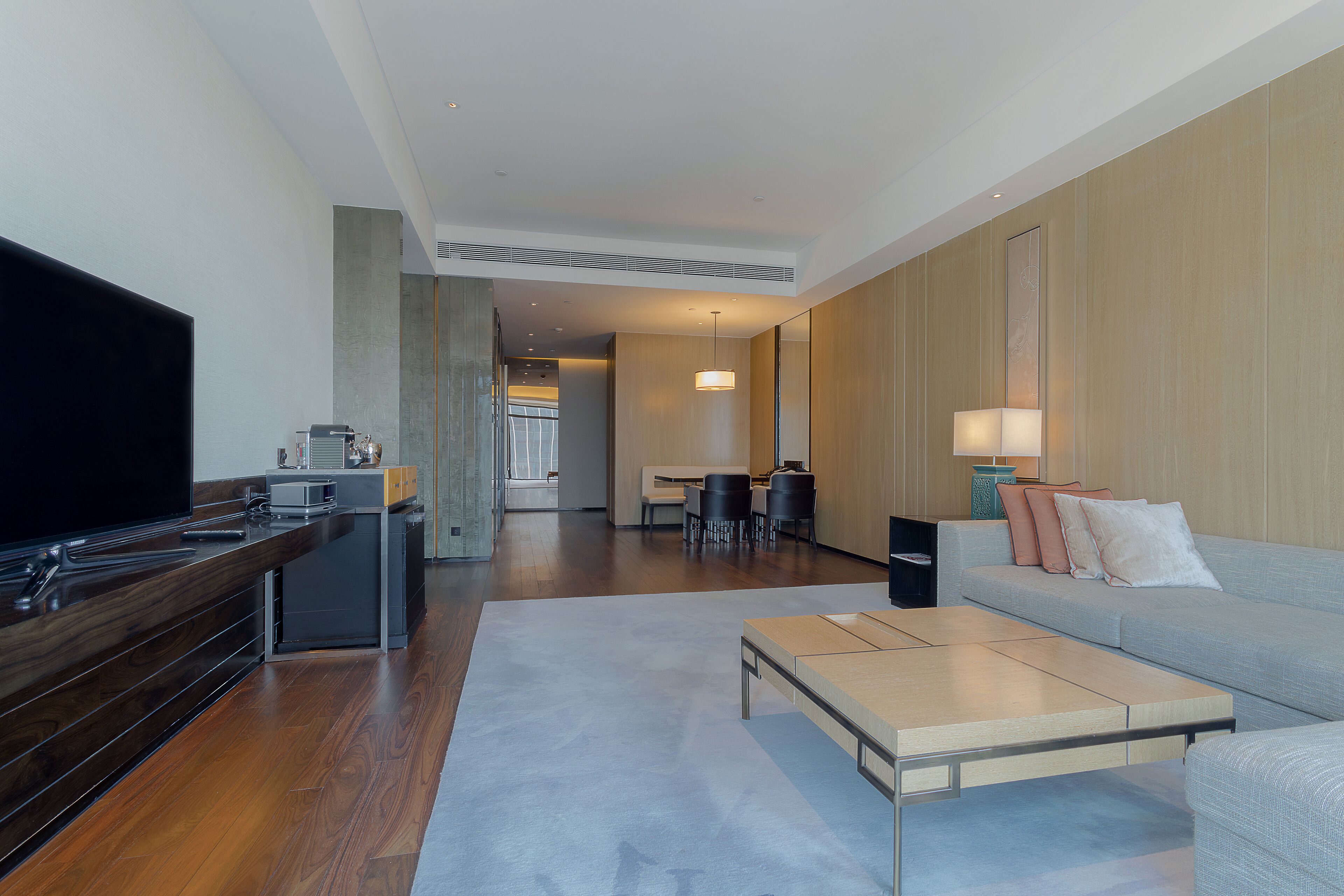 Habitación de hotel moderna con televisión de pantalla plana, zona de comedor y sofá.