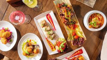 A variety of dishes on a wooden table, including grilled meats, salads, and appetizers.