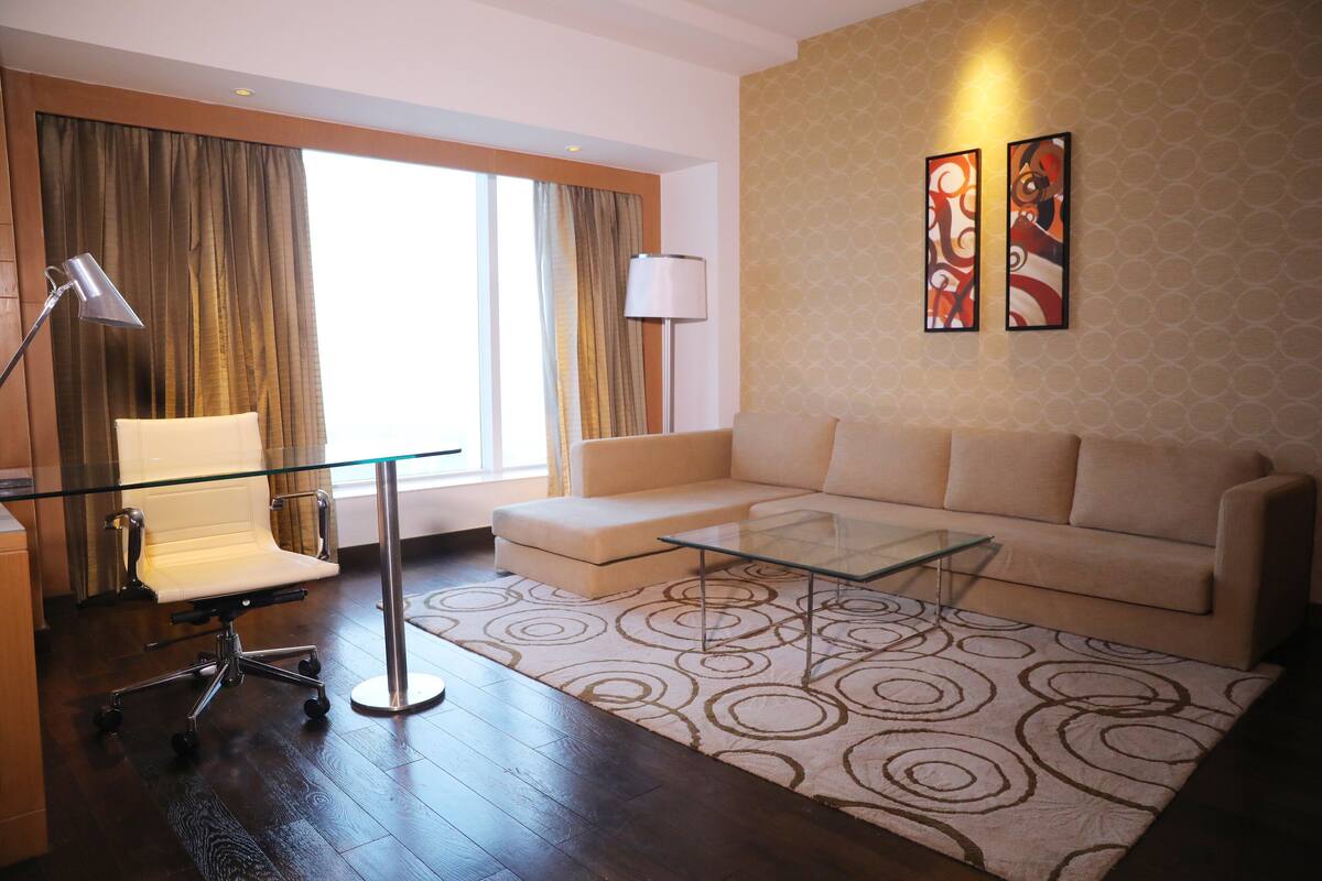 Una sala de estar moderna con una mesa de centro de vidrio, un sofá, una silla y una lámpara.