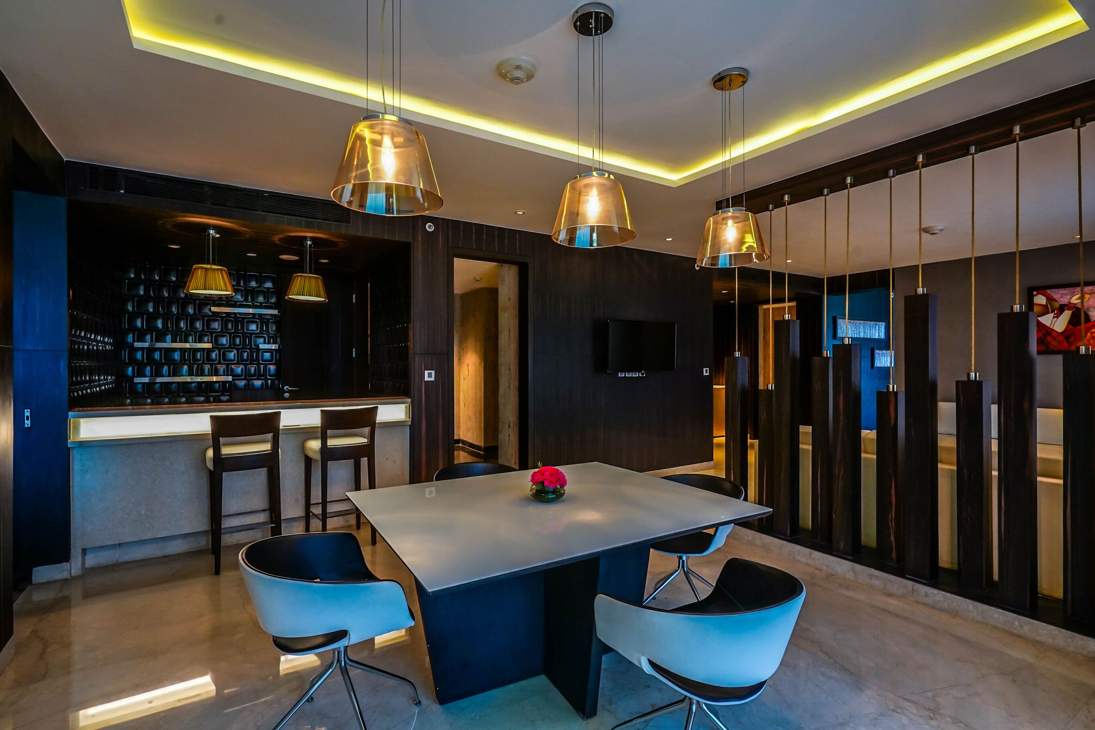 Un comedor moderno con barra, sillas contemporáneas e iluminación colgante.
