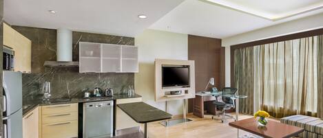 A modern kitchen with a built-in oven, a dishwasher, and a dining area with a table and chairs.