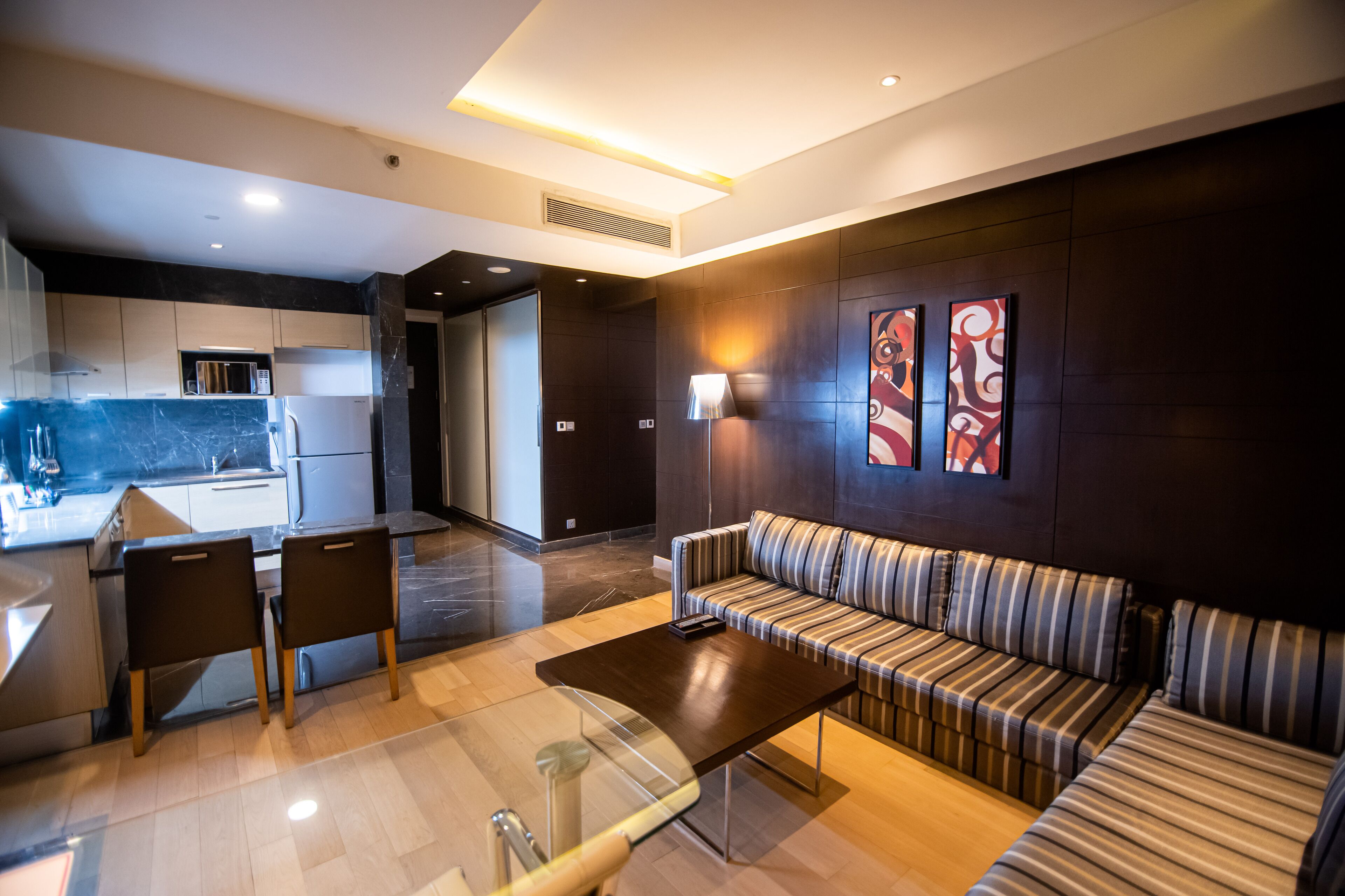Un espacio de sala moderno con un sofá, una mesa de centro y una mesa de comedor con sillas. Se ve un área de cocina al fondo.
