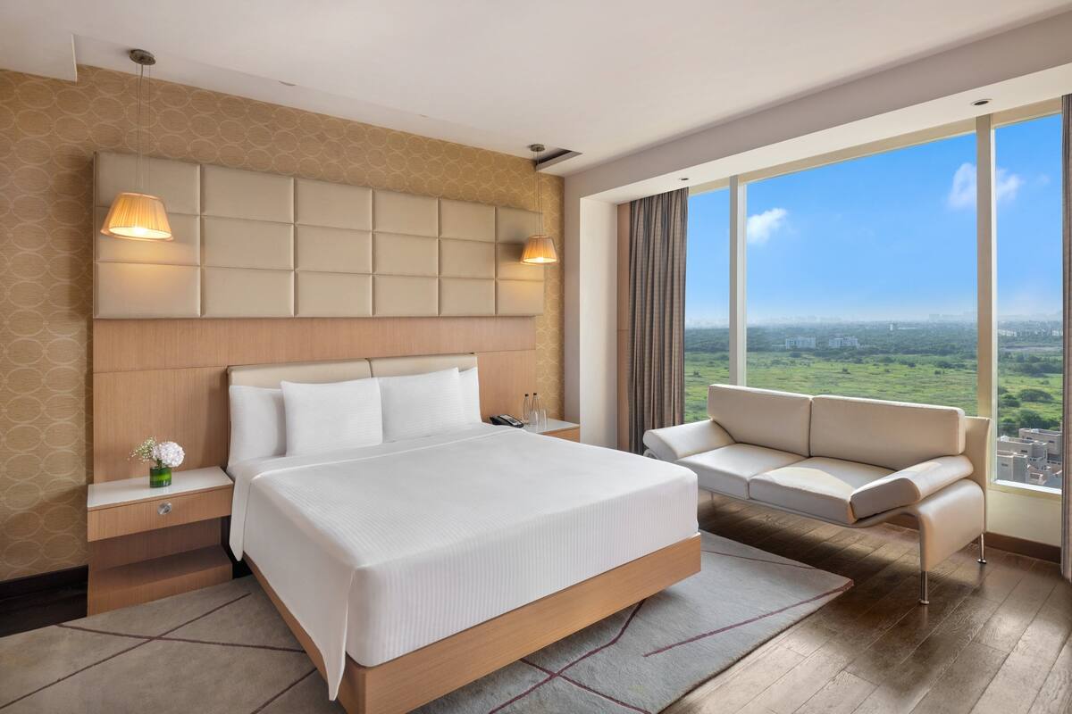 Una habitación de hotel moderna con una cama grande, un sofá y vistas a la ciudad.