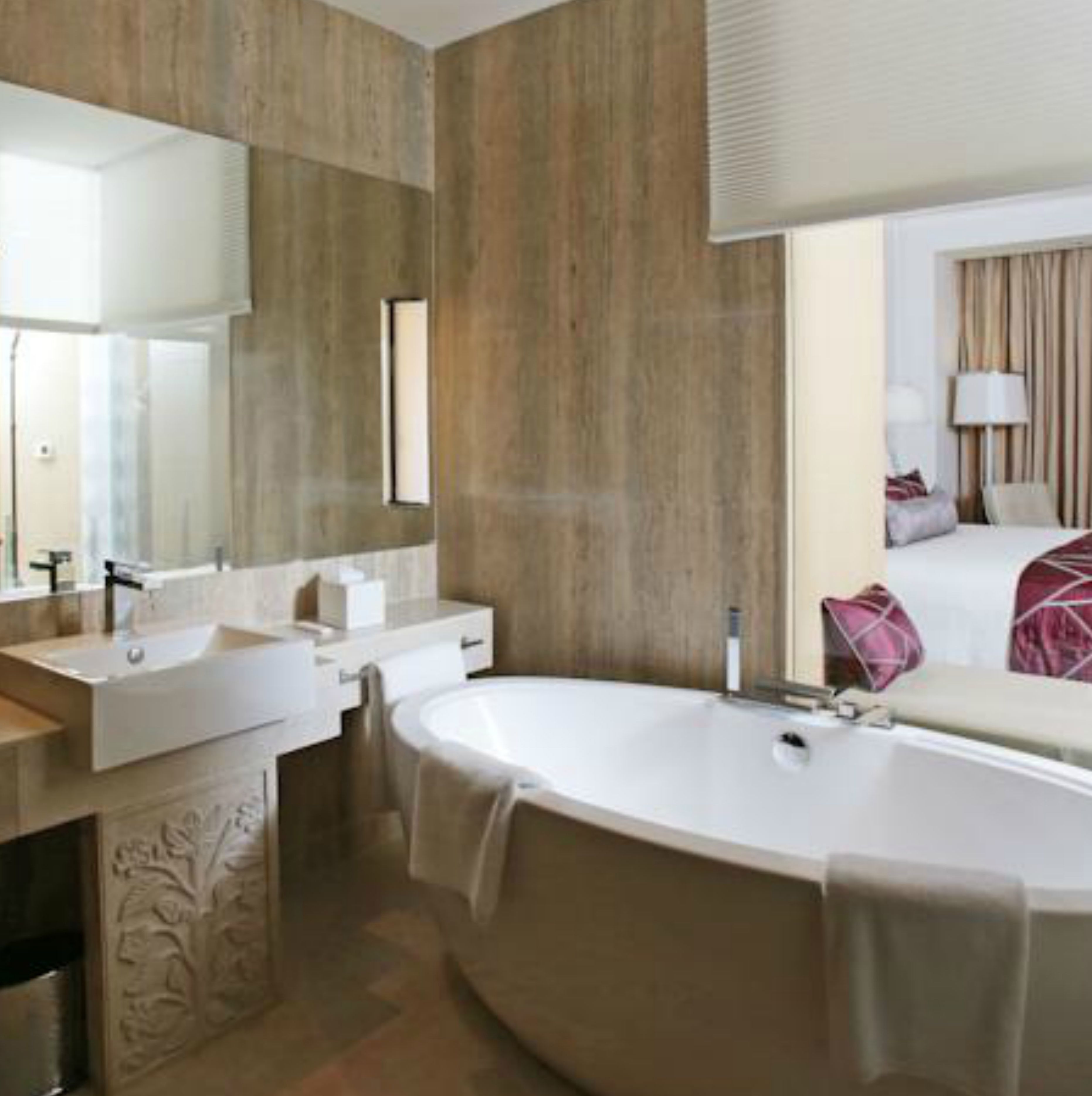 A modern bathroom with a freestanding bathtub, two sinks, and a large mirror.