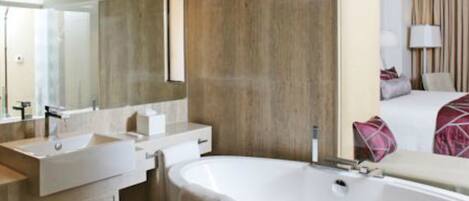 A modern bathroom with a freestanding bathtub, two sinks, and a large mirror.