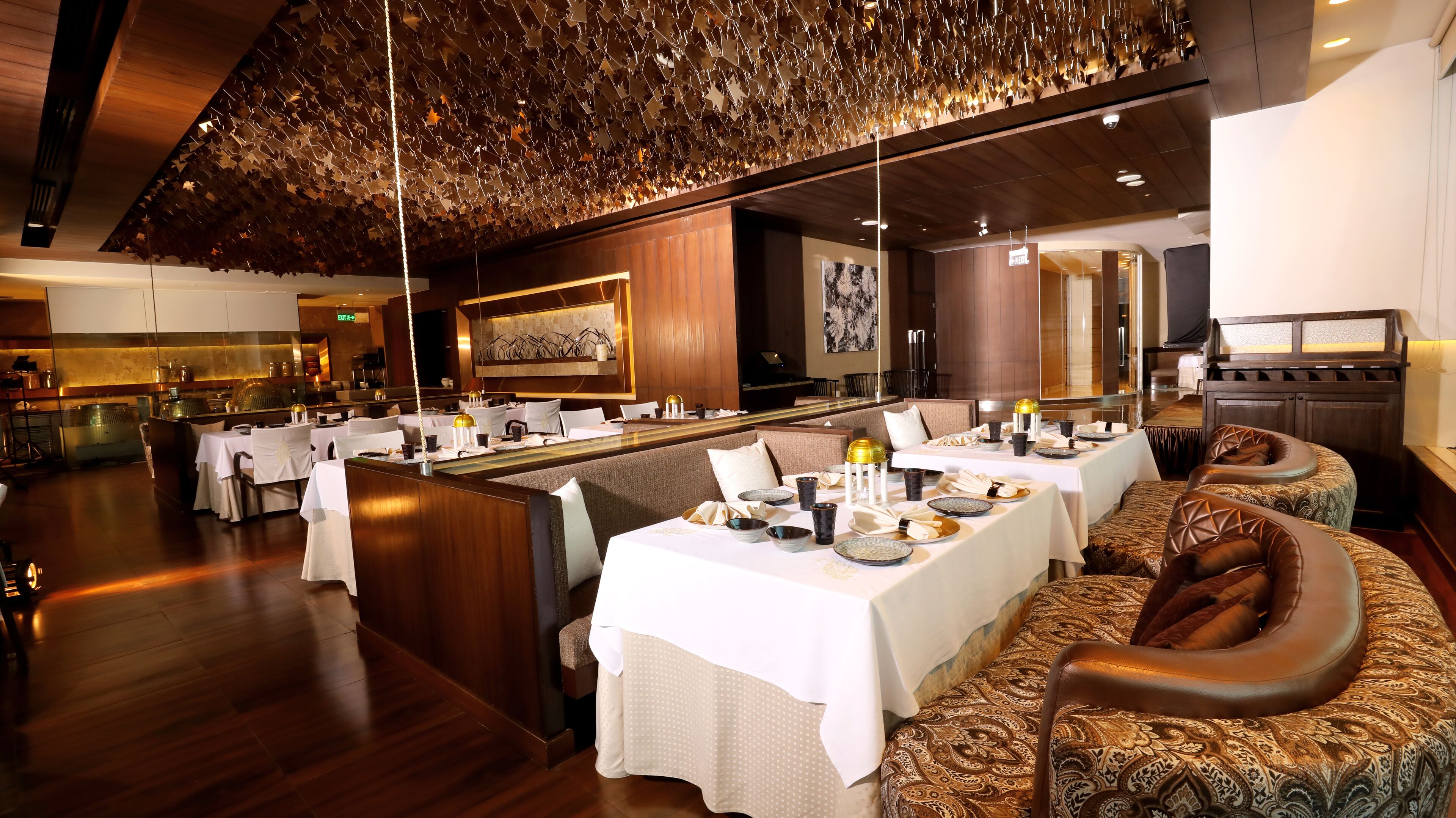 A restaurant with wooden flooring, white tablecloths, and leather seating.