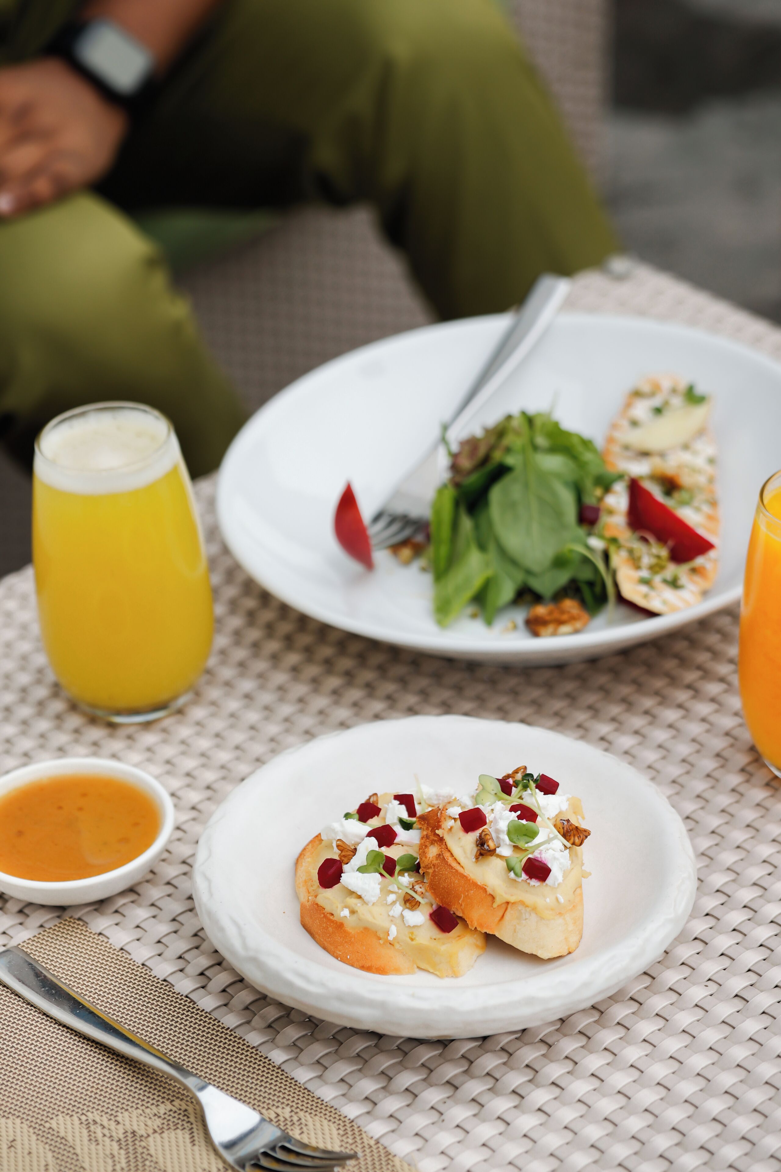 Una mesa con un plato de comida, un vaso de jugo de naranja y un tazón pequeño de salsa.