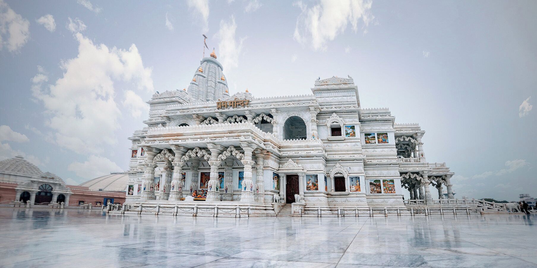 A white temple with intricate carvings and multiple domes.