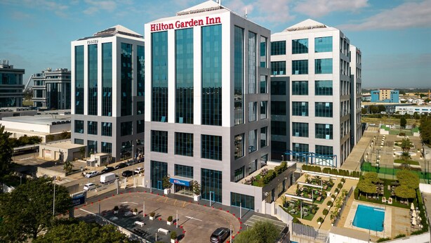A modern Hilton Garden Inn hotel with a central atrium, multiple floors, and a rooftop pool area. - Hilton Garden Inn Sevilla (Seville)