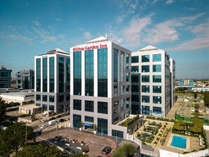 Ett modernt Hilton Garden Inn-hotell med en central atriumgård, flera våningar och ett poolområde p å taket.