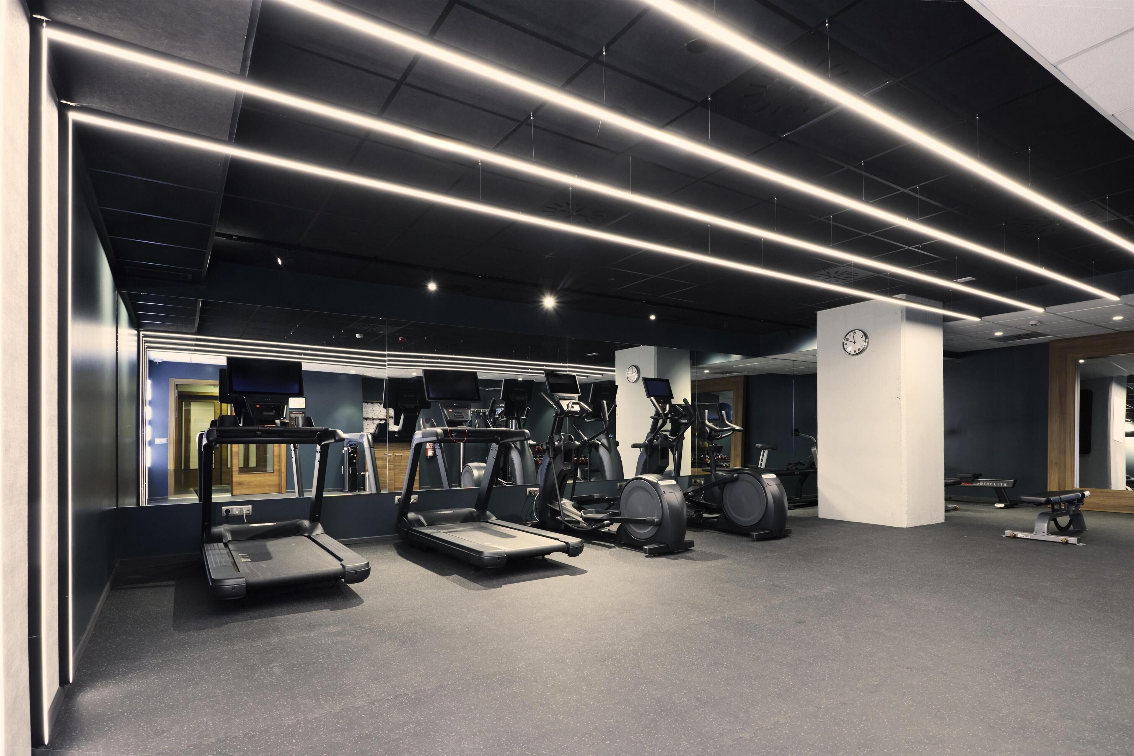 A modern gym with treadmills, elliptical machines, and stationary bikes.