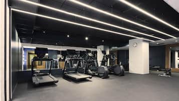 Un gimnasio moderno con cintas de correr, elípticas y bicicletas estáticas.