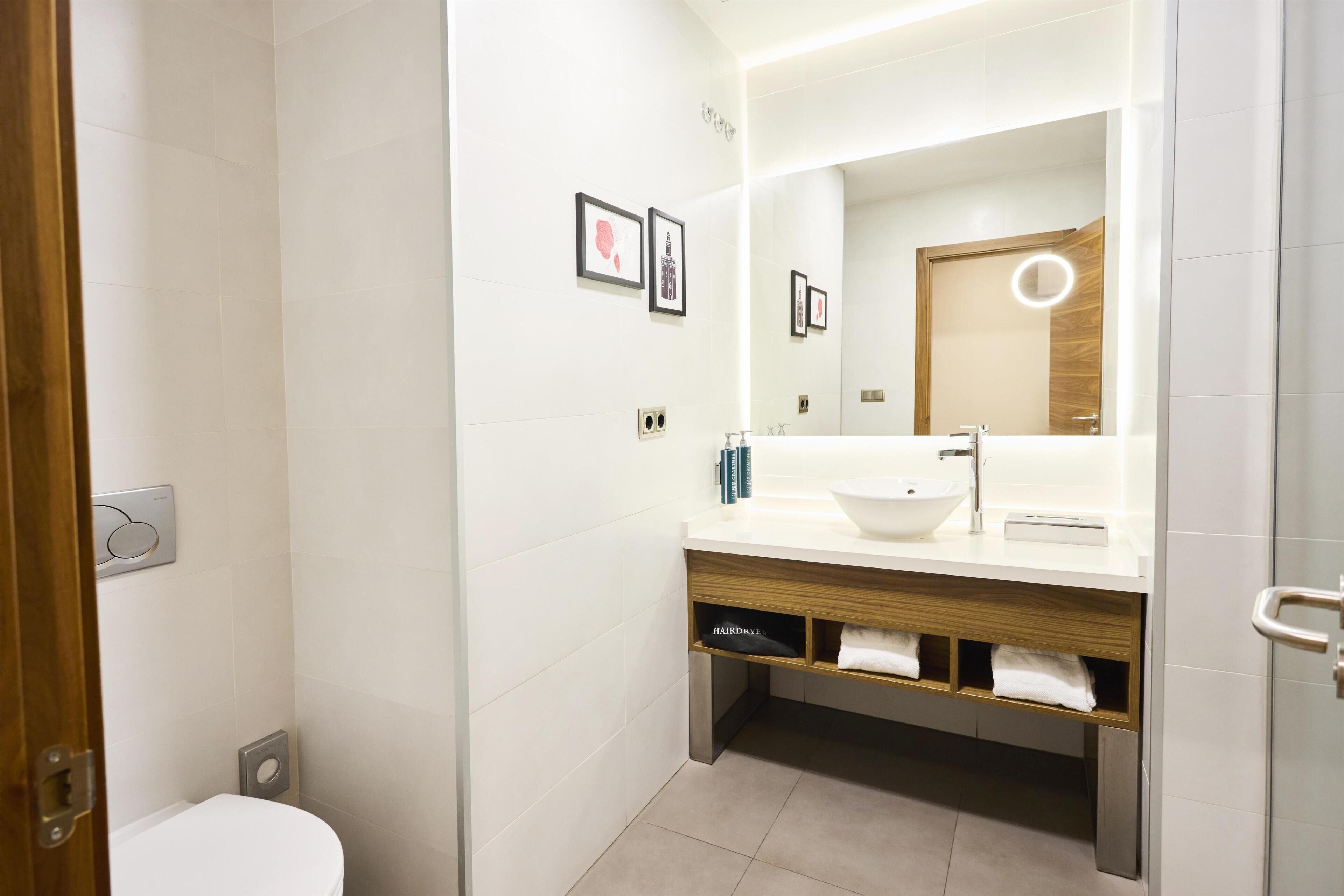 A modern bathroom with a white toilet, a sink with a mirror, and a towel rack.