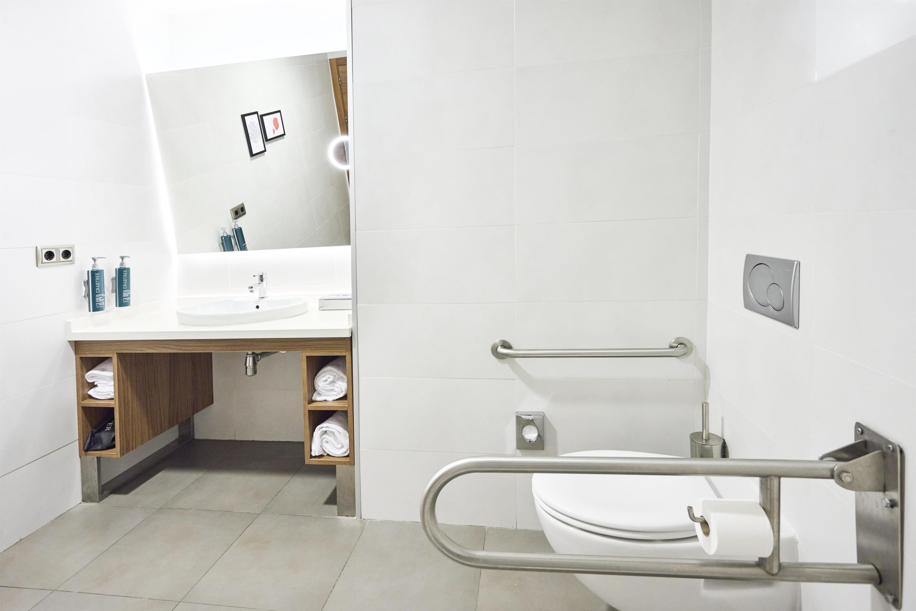 Un baño moderno con un lavamanos, espejo y retrete blancos.