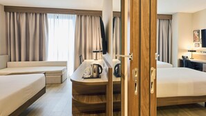 A hotel room with two beds, a desk with a kettle, a chair, and a television. - Hilton Garden Inn Sevilla (Seville)