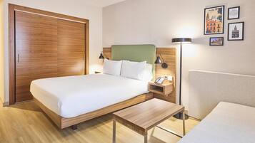 Quarto de hotel com cama, mesa de cabeceira, luminária e obra de arte na parede.