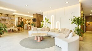 A modern living area with a curved sofa, a round coffee table, and a reception desk. - Hilton Garden Inn Sevilla (Seville)