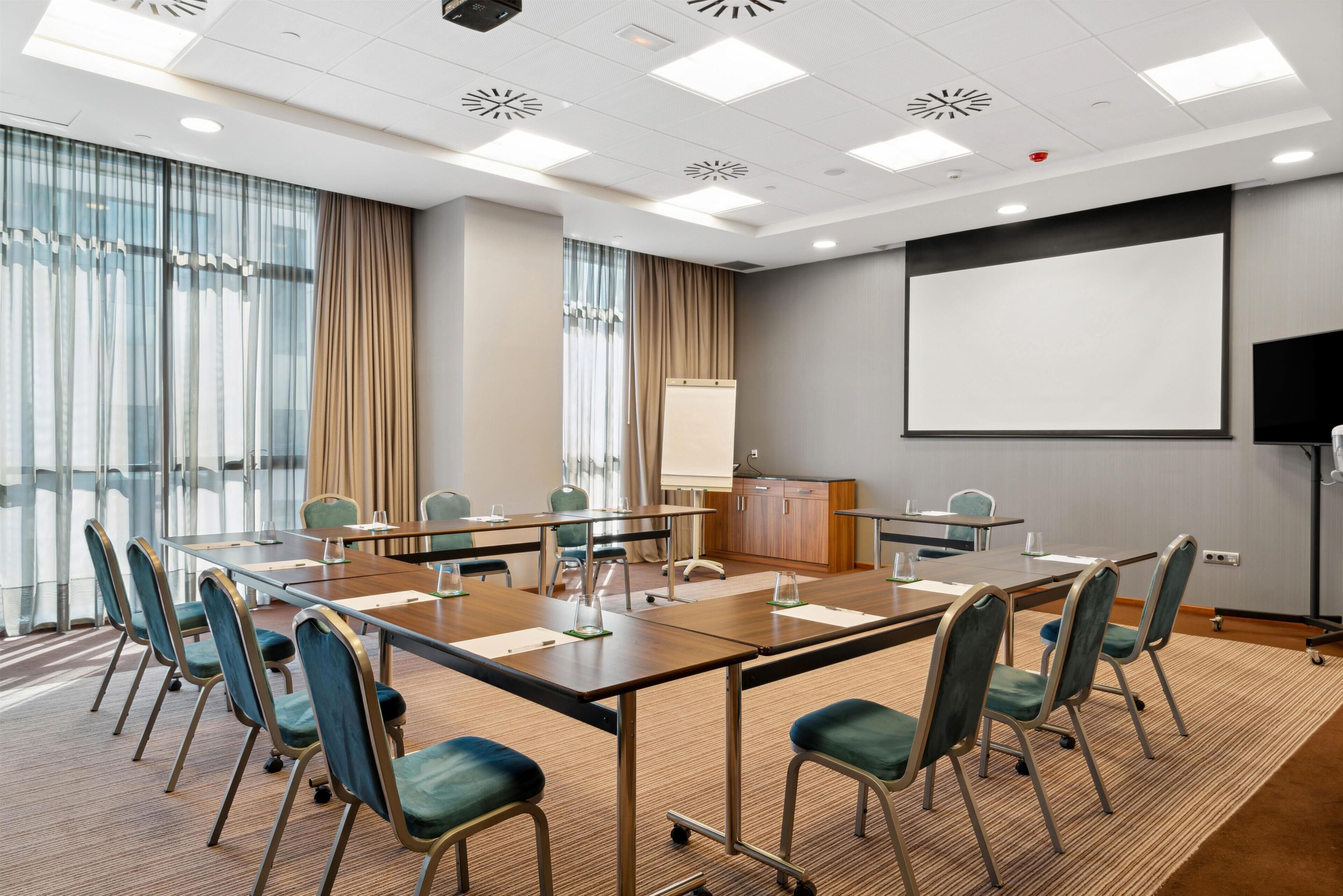 A conference room with a large table, chairs, a projector screen, and a whiteboard.
