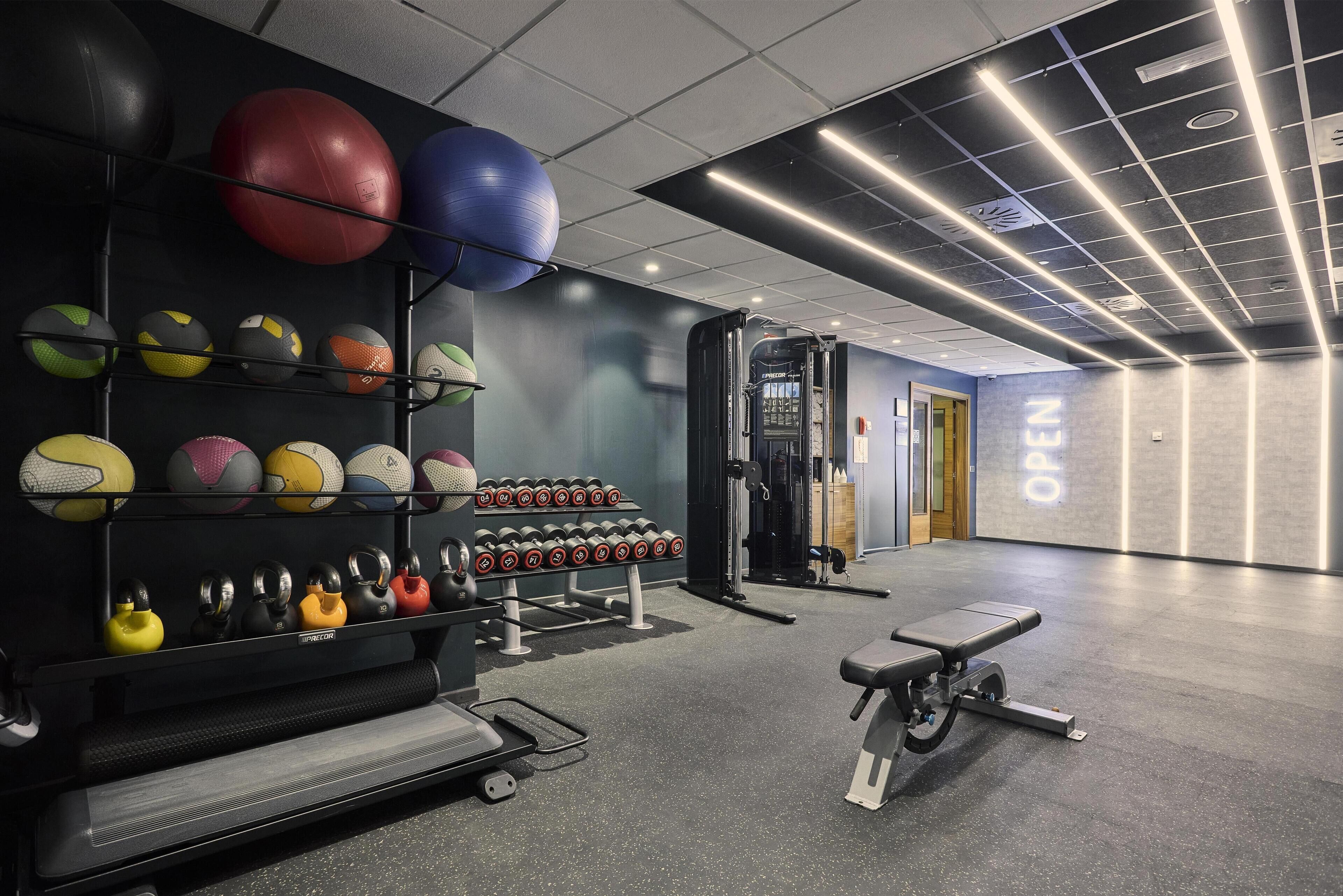 A gym with exercise equipment, a bench, and a wall with 'OPEN' sign.
