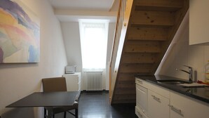 Eine Küche mit einer Holztreppe, einem Esstisch und einem weißen Heizkörper.