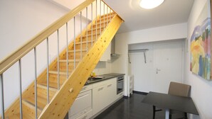 Eine moderne Küche mit einer Holztreppe, einem Essbereich mit Tisch und Stühlen sowie einer Kücheninsel.