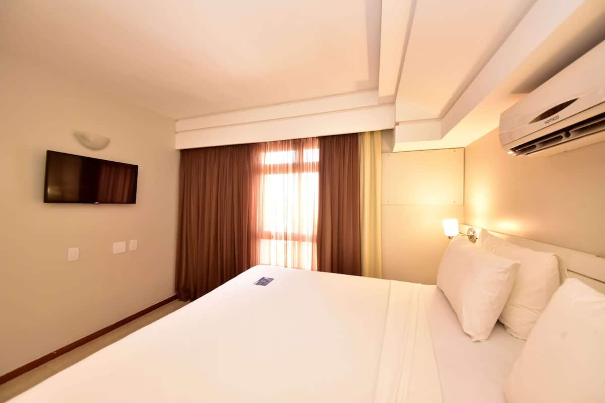Enjoy a restful stay in this cozy room with a comfortable bed, flat-screen TV, and air conditioning unit.