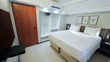 Quarto de hotel com uma cama, um guarda-roupa, uma escrivaninha e um espelho.