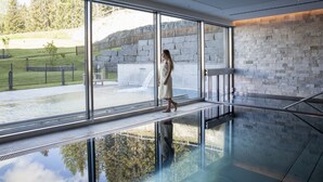 A modern interior with large windows, a stone wall, and a glass floor. - AlpenGold Davos (Davos)
