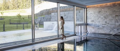A modern interior with large windows, a stone wall, and a glass floor.