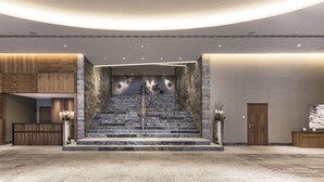 A modern lobby with a marble staircase, wooden reception desk, and a large reception area. - AlpenGold Davos (Davos)